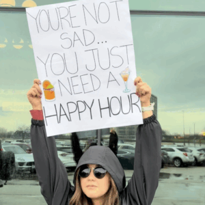 a woman holding a sign saying you're not sad you just need happy hour